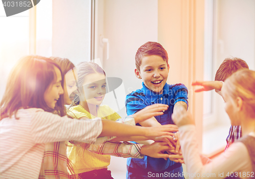 Image of group of smiling school kids putting hands on top