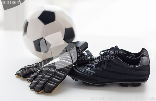 Image of close up of soccer ball, boots and gloves on table