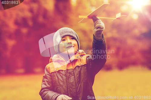 Image of happy little boy playing with toy plane outdoors