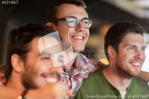 Image of happy male friends watching football at bar or pub