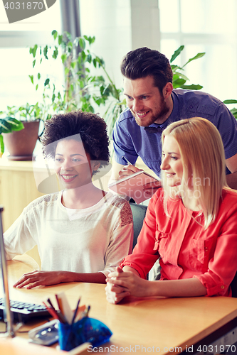 Image of happy creative team with computer in office