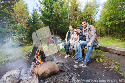 Image of happy family sitting on bench at camp fire