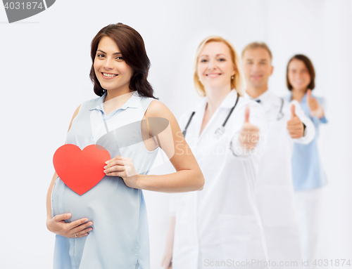 Image of happy pregnant woman with red heart touching belly