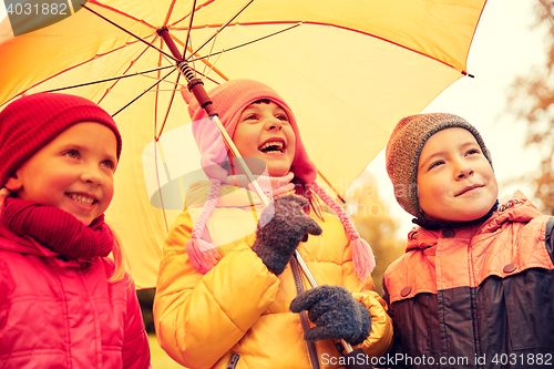 Image of happy children with umbrella in autumn park