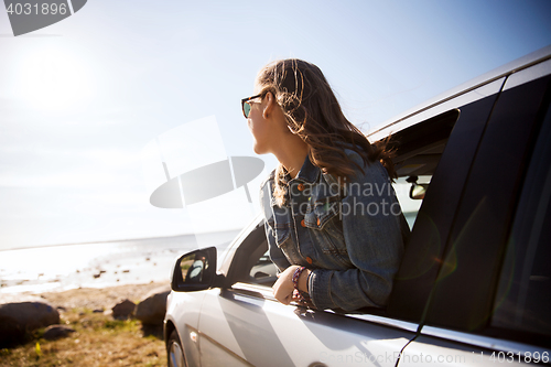 Image of happy teenage girl or young woman in car