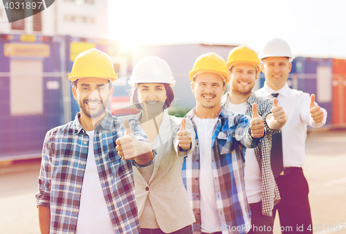 Image of group of smiling builders in hardhats outdoors