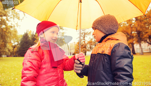 Image of happy boy and girl with umbrella in autumn park