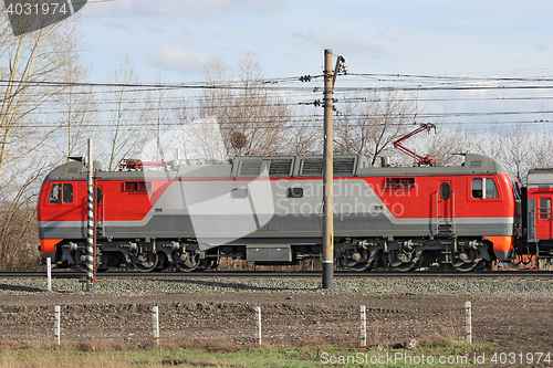 Image of Red locomotive on electricity coming by rail.