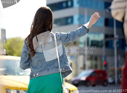 Image of young woman or girl catching taxi on city street