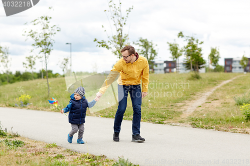 Image of happy father and son with pinwheel toy outdoors