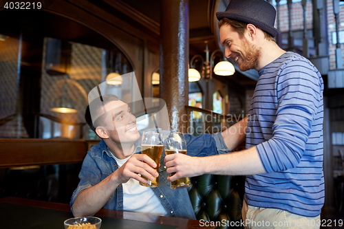 Image of happy male friends drinking beer at bar or pub