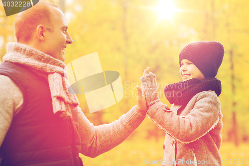 Image of happy father and son making high five in park