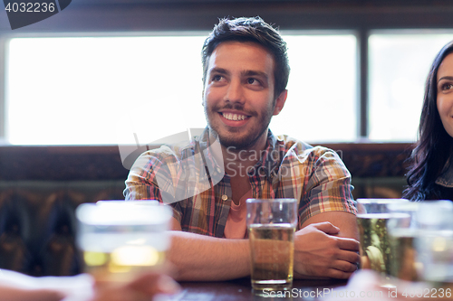 Image of happy friends drinking beer at bar or pub