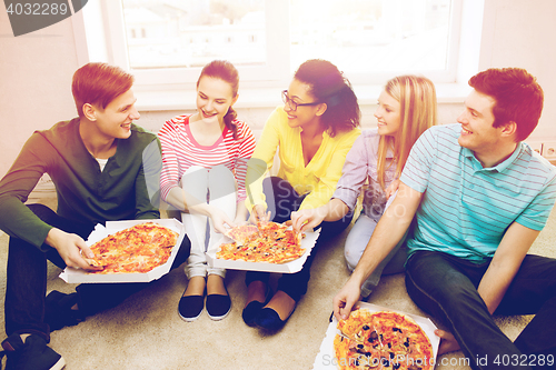 Image of five smiling teenagers eating pizza at home