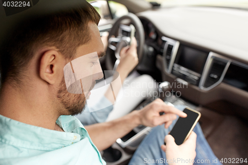 Image of man and woman with smartphones driving in car