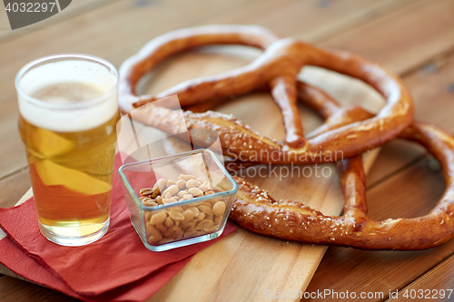 Image of close up of beer, pretzels and peanuts on table