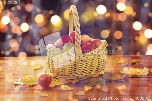 Image of close up of basket with apples on wooden table