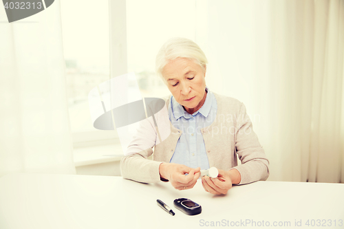 Image of senior woman with glucometer checking blood sugar