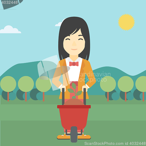 Image of Woman with plant and wheelbarrow.