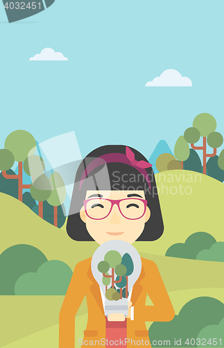 Image of Woman with lightbulb and trees inside.