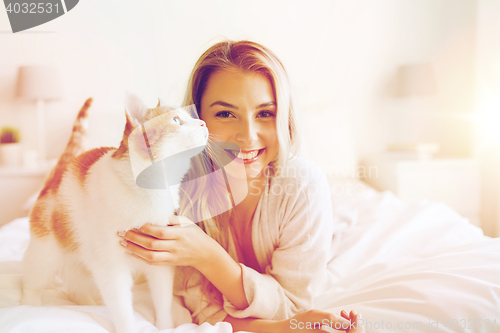 Image of happy young woman with cat in bed at home