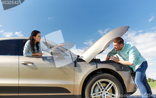 Image of couple with open hood of broken car at countryside