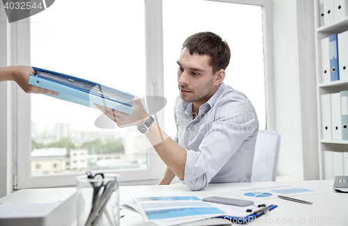 Image of businessman taking papers from secretary in office