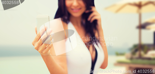 Image of young woman taking selfie with smartphone on beach