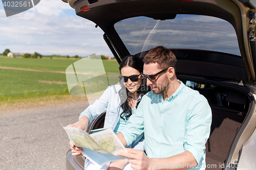 Image of happy man and woman with road map at hatchback car