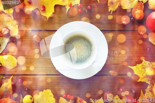 Image of close up of coffee cup on table with autumn leaves