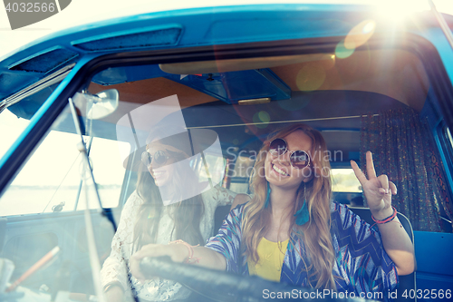 Image of smiling young hippie women driving minivan car