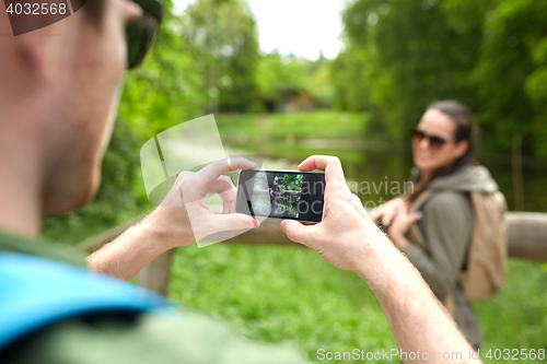 Image of couple with backpacks taking picture by smartphone
