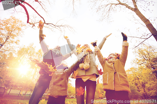 Image of happy family playing with autumn leaves in park