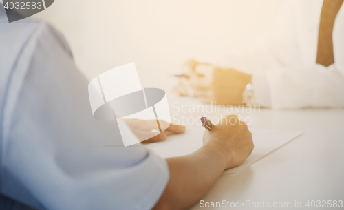 Image of close up of doctor taking notes at hospital