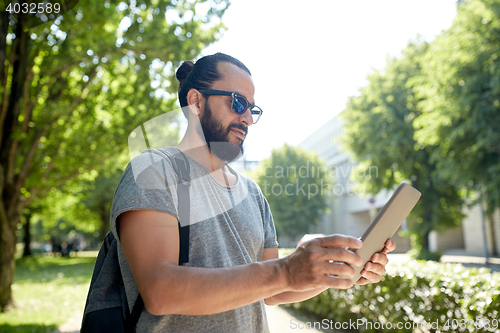 Image of man traveling with backpack and tablet pc in city