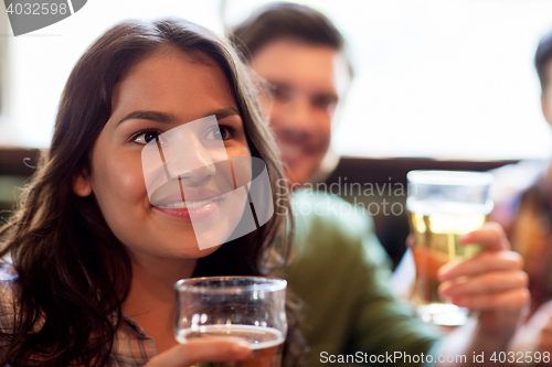 Image of happy woman with friends drinking beer at pub