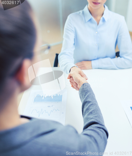 Image of two calm businesswoman shaking hands in office