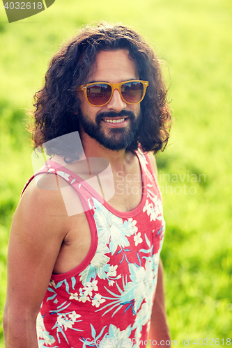 Image of smiling young hippie man on green field