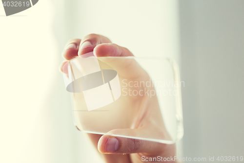 Image of close up of male hand with transparent smartphone