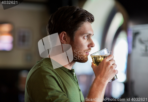 Image of young man drinking beer at bar or pub