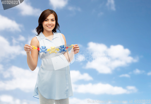 Image of happy pregnant woman holding rattle toy