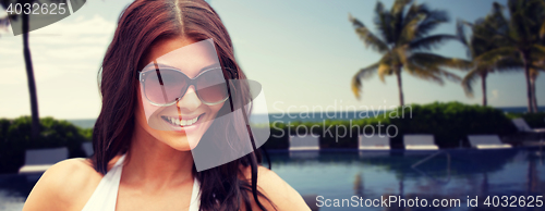 Image of smiling young woman with sunglasses on beach