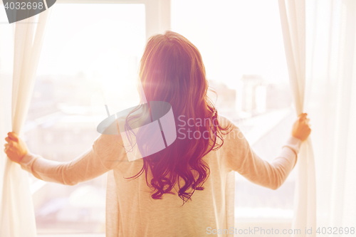 Image of close up of woman opening window curtains