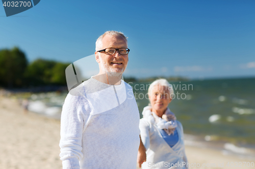 Image of happy senior couple holding hands on summer beach