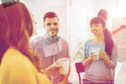 Image of happy creative team drinking coffee at office