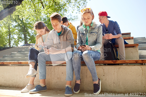 Image of group of teenage friends with smartphones outdoors
