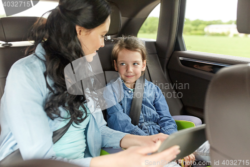 Image of happy family with tablet pc driving in car