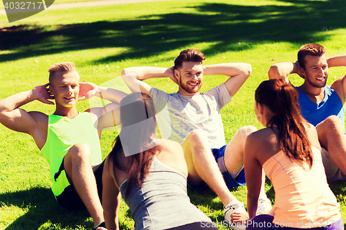 Image of group of friends or sportsmen exercising outdoors