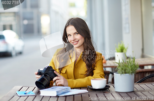 Image of happy tourist woman with camera at city cafe