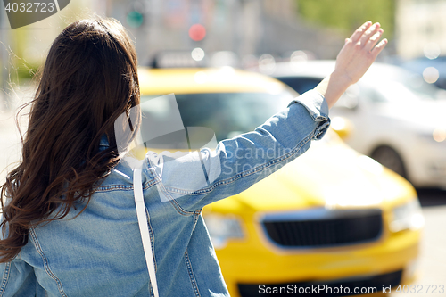 Image of young woman or girl catching taxi on city street